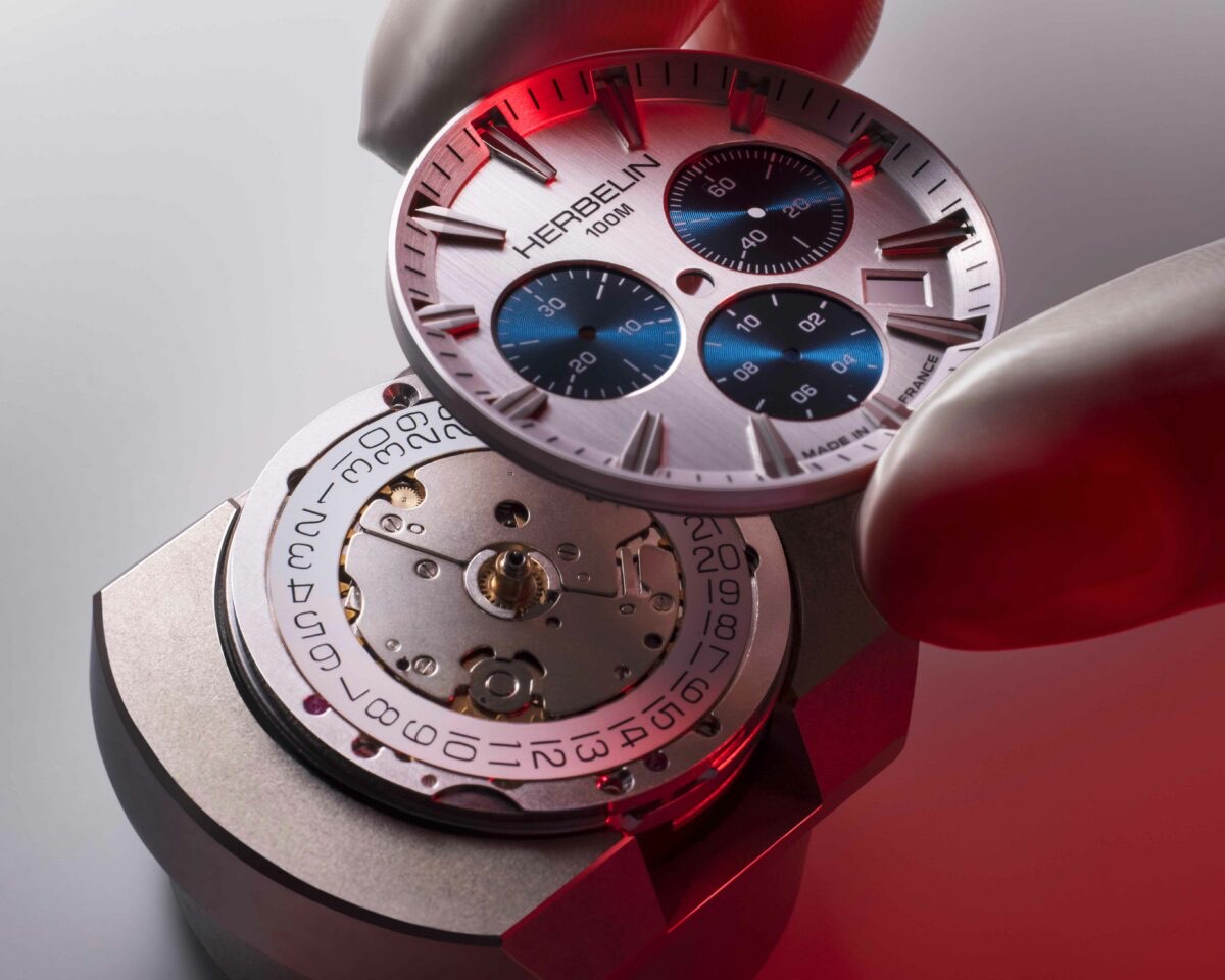 Uhrmacher setzt ein Chronographen-Zifferblatt von HERBELIN auf das Uhrwerk